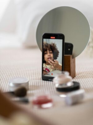 A beauty influencer vlogs a makeup tutorial using a smartphone indoors.