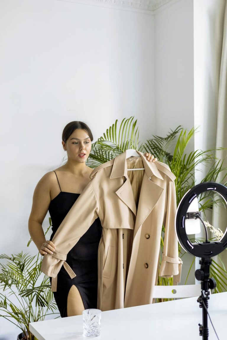 A fashionable woman vlogging about a stylish beige trench coat indoors.