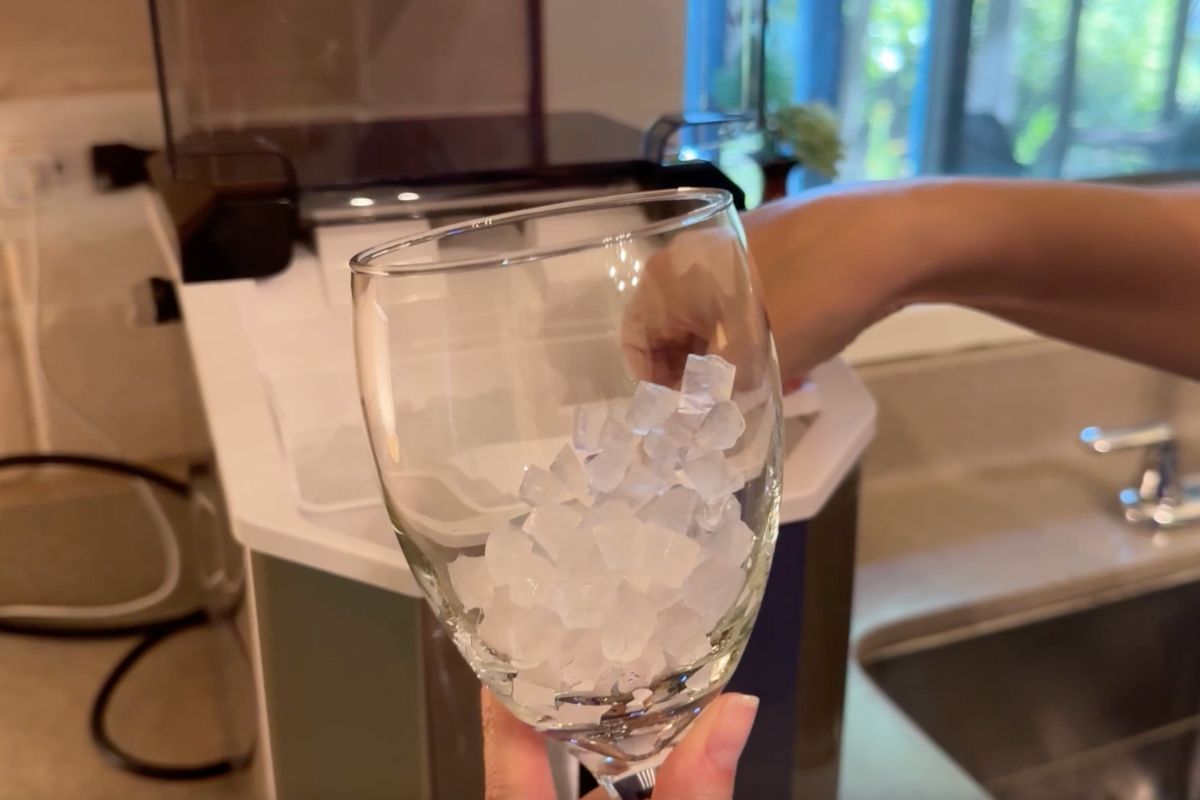 Holding a glass of nugget ice in front of ice maker