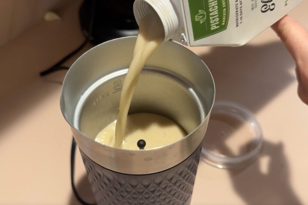 pouring pistachio milk into milk frother