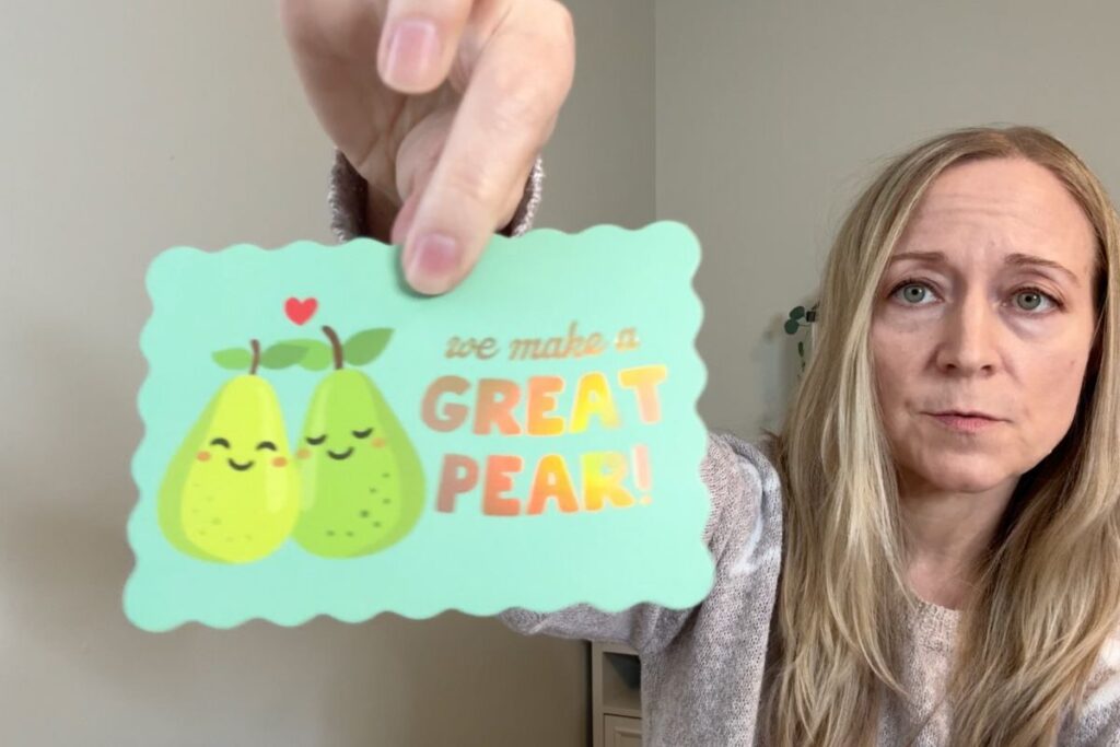 Holding a mini valentine card with pears on it. 