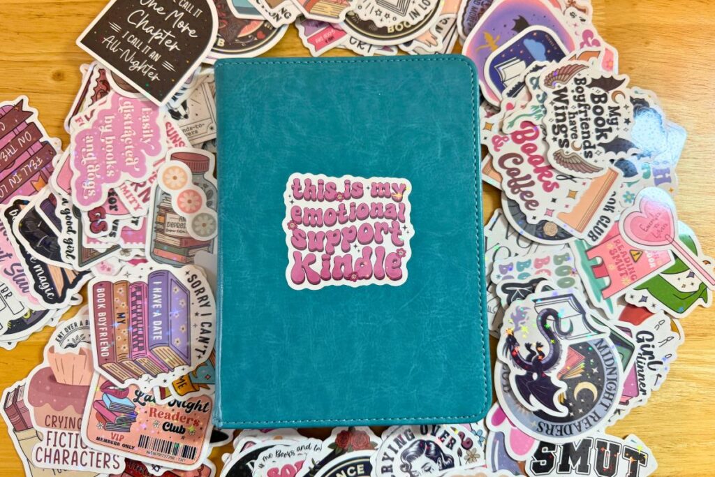 Kindle case with a sticker surrounded by romantasy book stickers