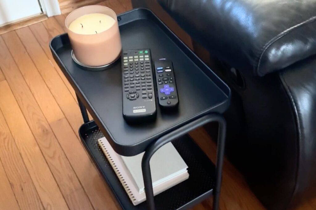 side table with candle, remotes, and books on it