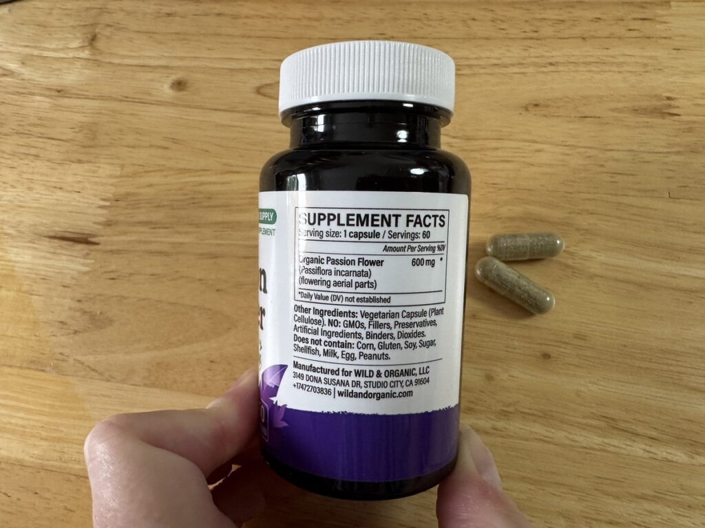 Hand holding the Wild and Organic Passion Flower bottle to show the supplement facts panel