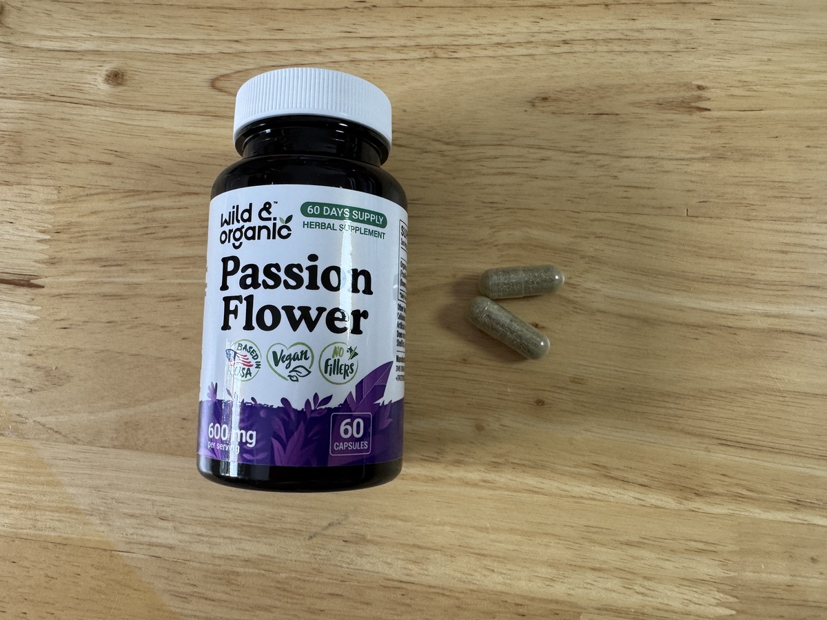 Wild and Organic Passion Flower 600mg bottle on a wood surface with two capsules beside it
