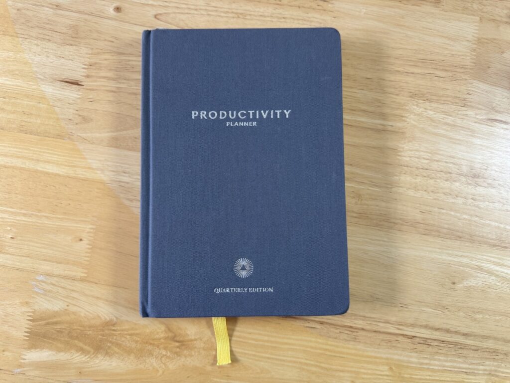 Closed gray Productivity Planner Quarterly Edition cover with yellow ribbon bookmark