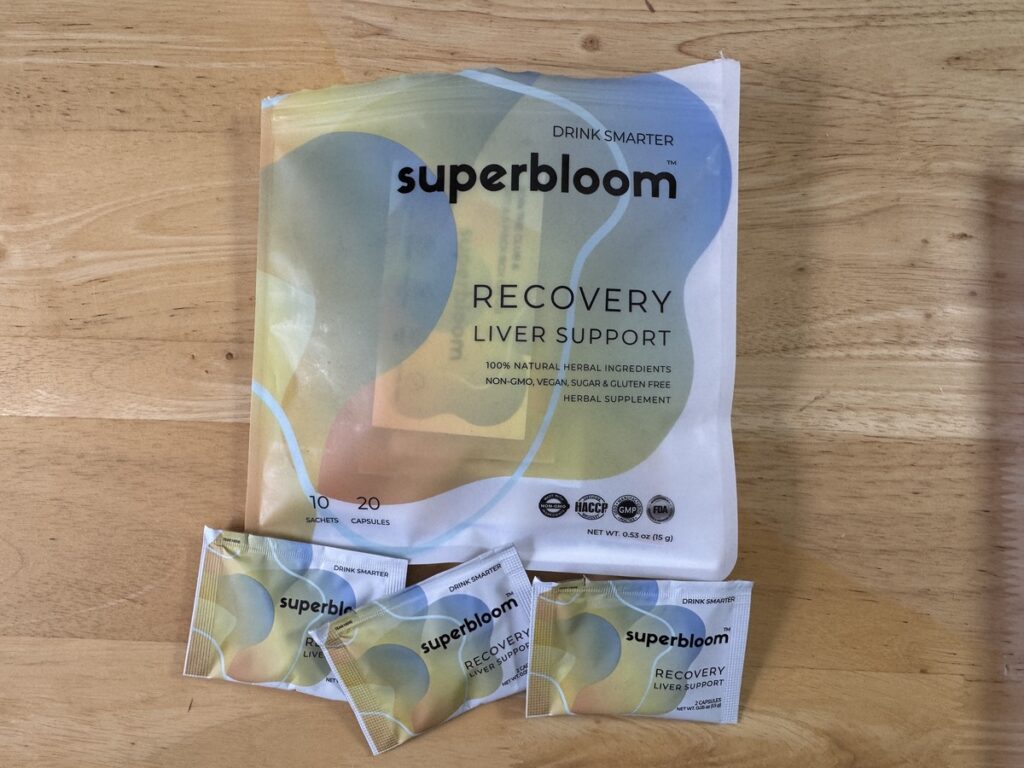 Superbloom Recovery liver support pouch on a wood surface with three single-serve sachets in front