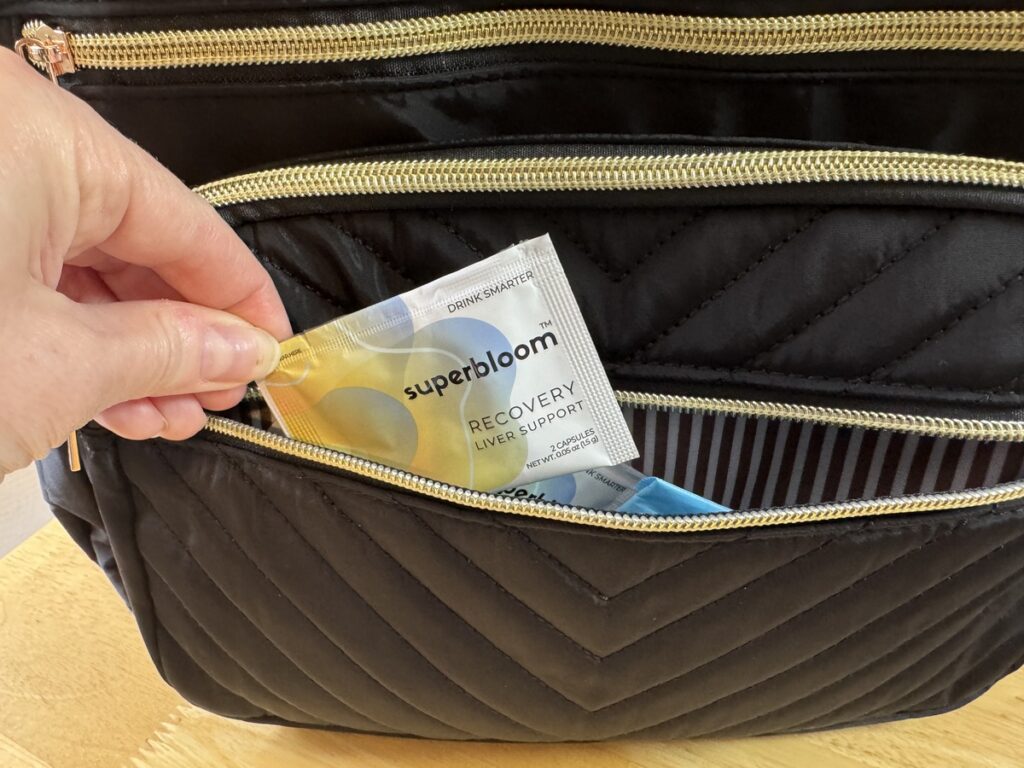 Hand tucking a Superbloom Recovery sachet into a quilted black travel pouch