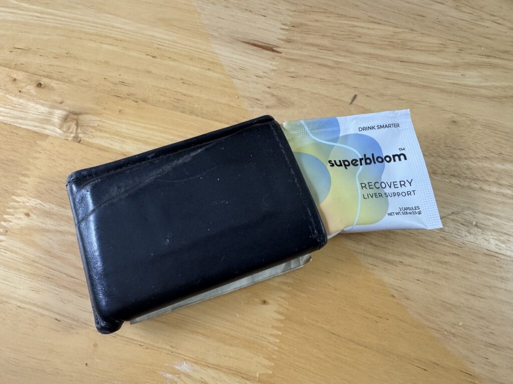 Superbloom Recovery sachet next to a folded black leather wallet for size comparison