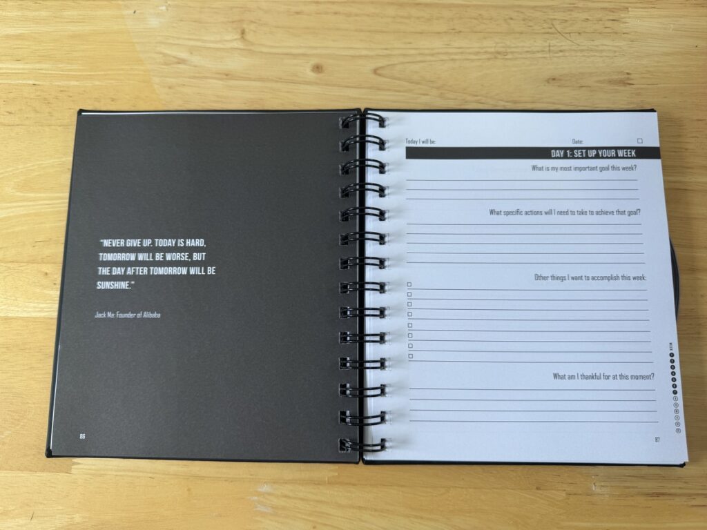 Open spiral planner on wood desk, Jack Ma quote on left page, Day 1 Set Up Your Week prompts on right page.