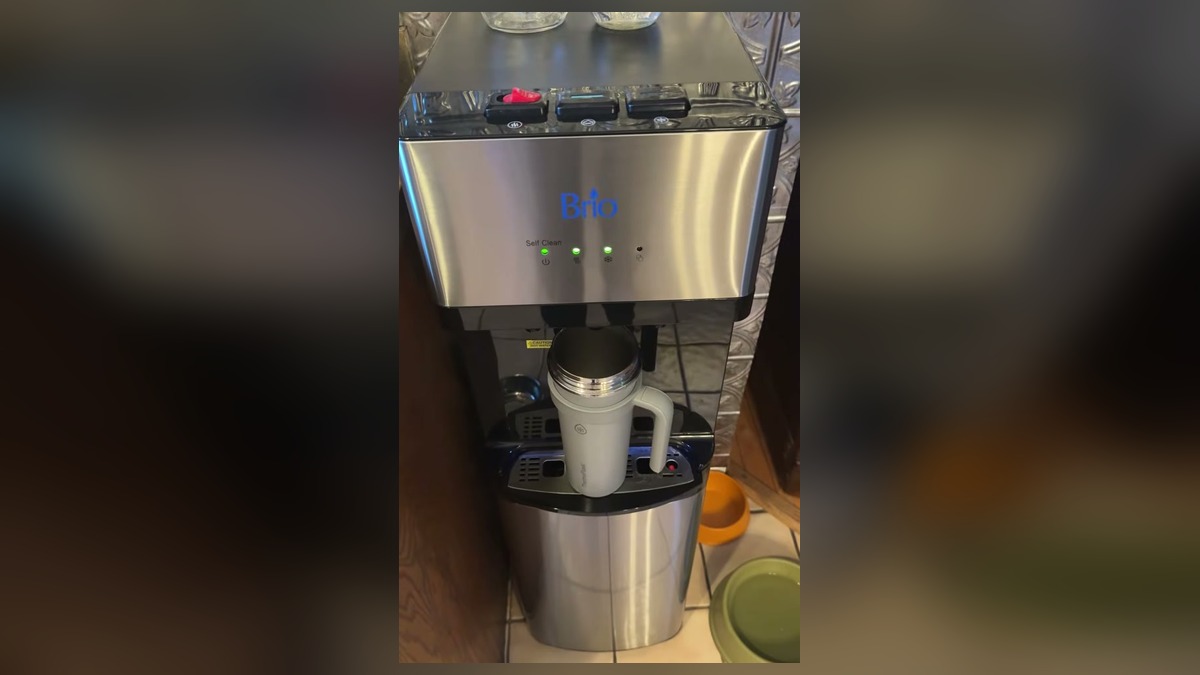 Brio self cleaning bottom loading water dispenser in stainless steel with a tall insulated tumbler standing upright under the spouts