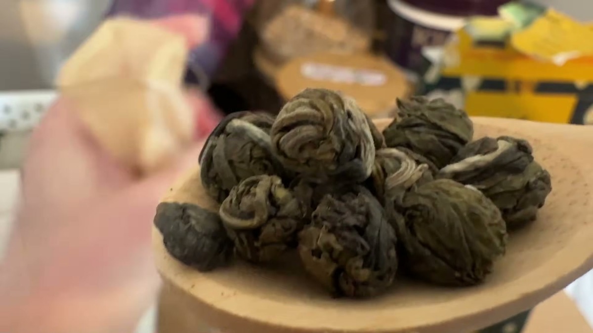 Close-up of Enzo hand-rolled jasmine green tea pearls, tight dark green balls on a wooden spoon