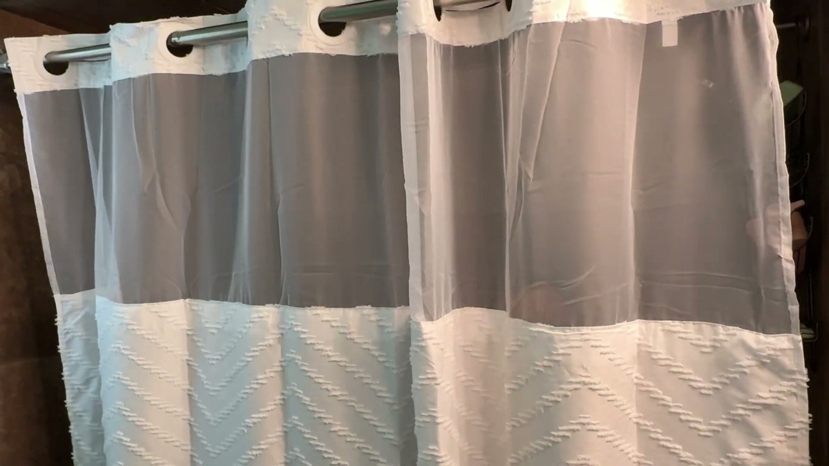 FADOTY white no hook shower curtain hanging on a rod by its built-in rings, with a sheer mesh window across the top and a tufted chevron pattern below
