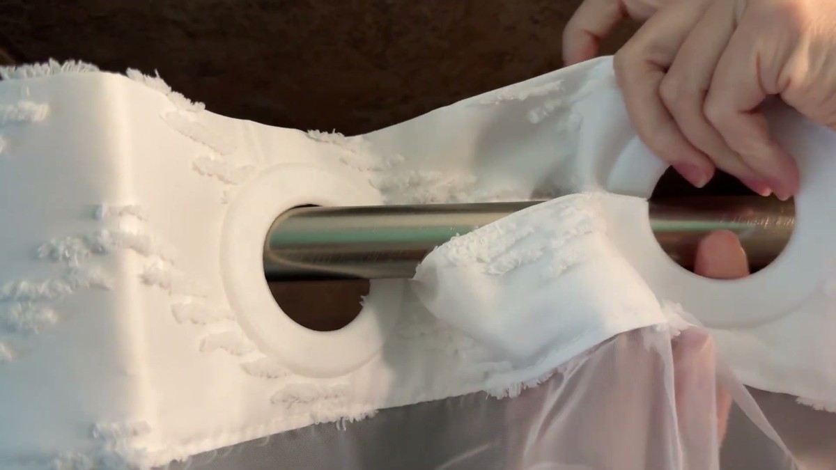 Close-up of the FADOTY shower curtain's built-in rings slid over a brushed metal shower rod, no hooks needed