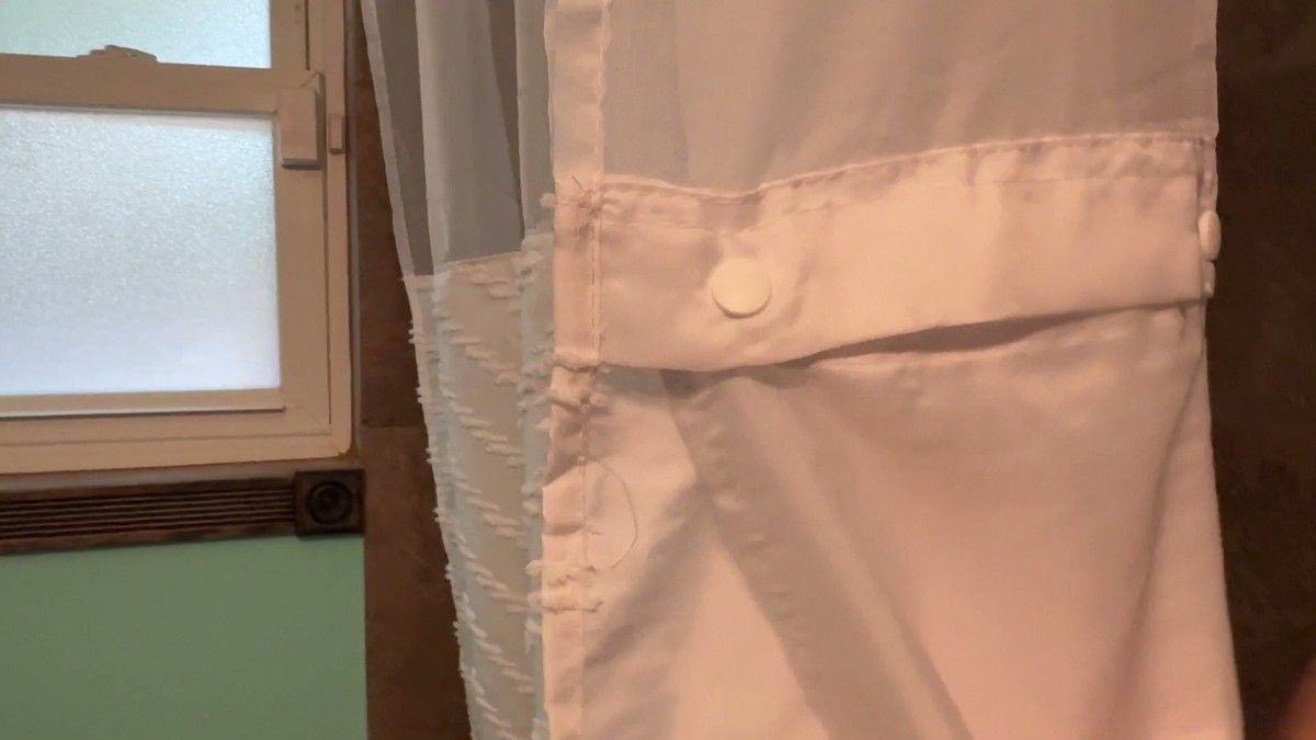 The white snap-in liner attached behind the FADOTY shower curtain with round plastic snaps along its top edge