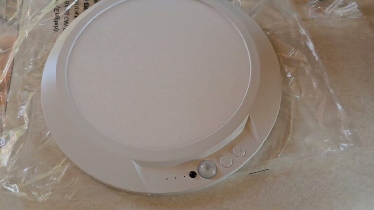 Fsaox rechargeable motion sensor ceiling light, a white round LED panel with the motion sensor and two buttons on the rim, out of the box on a counter