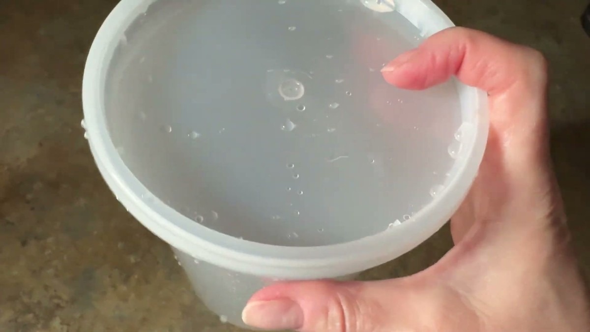 A GUSTO deli container full of water with the snap lid sealed on, water beaded across the lid after the shake test