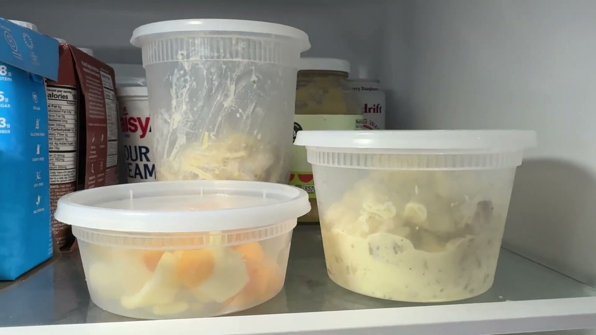 Three GUSTO deli containers on a fridge shelf with lids snapped on, holding cut fruit and potato salad