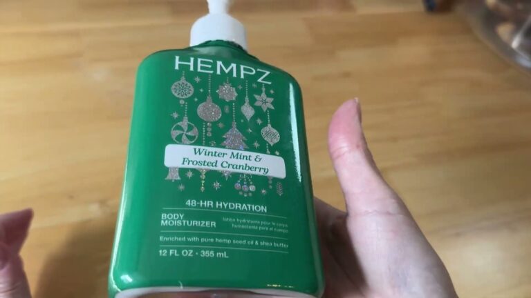 Green 12 ounce pump bottle of Hempz Holiday Mint body lotion in Winter Mint and Frosted Cranberry held up on a wooden table