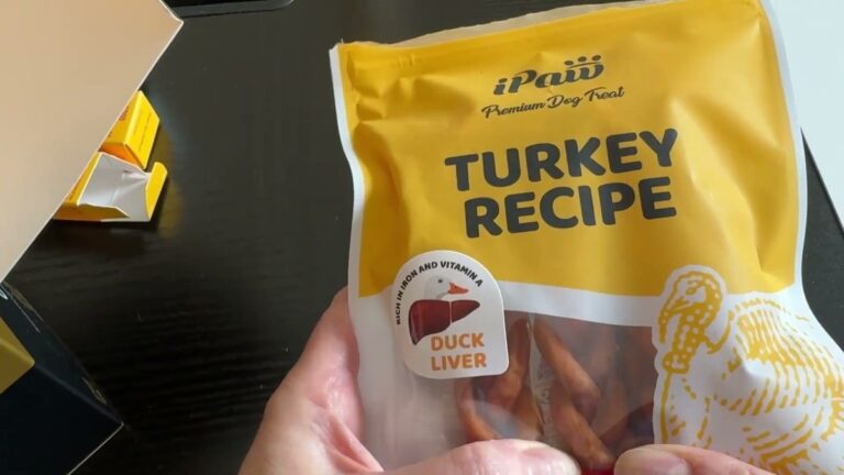iPaw Turkey Recipe dog treats bag held in two hands, yellow front label with a duck liver badge and braided turkey sticks showing through the clear window