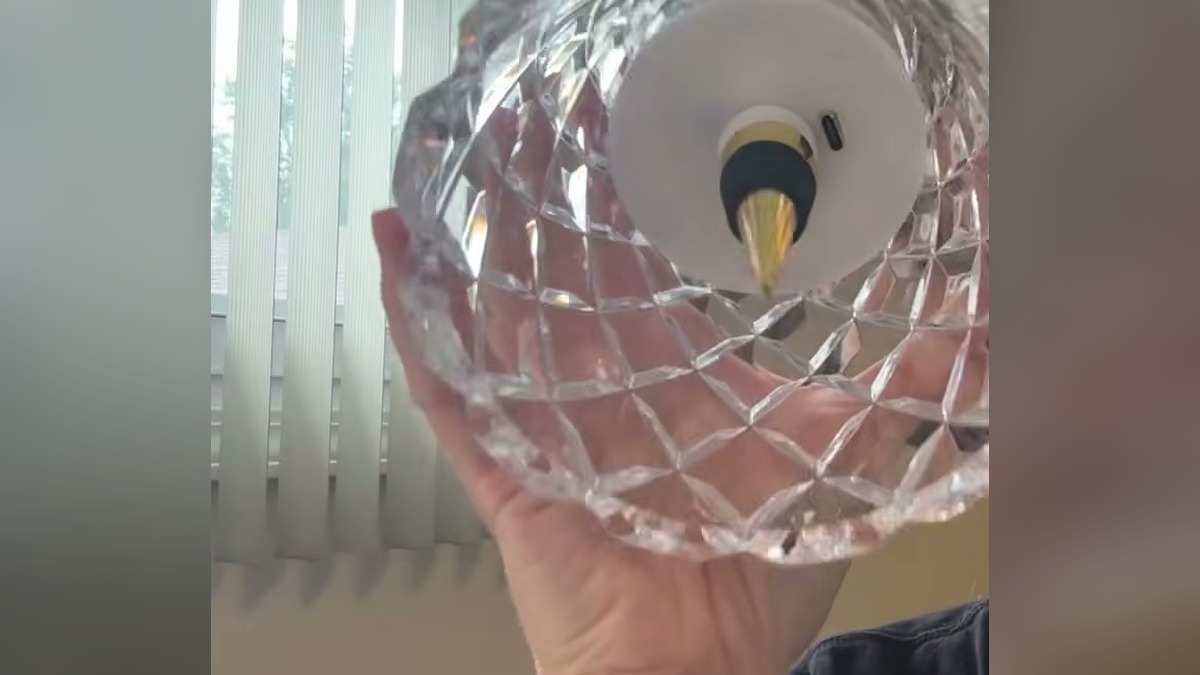 Underside of the Jiofaviu lamp shade held in a hand, showing the tapered gold metal wine stopper, the white LED housing around it and the USB-C charging port