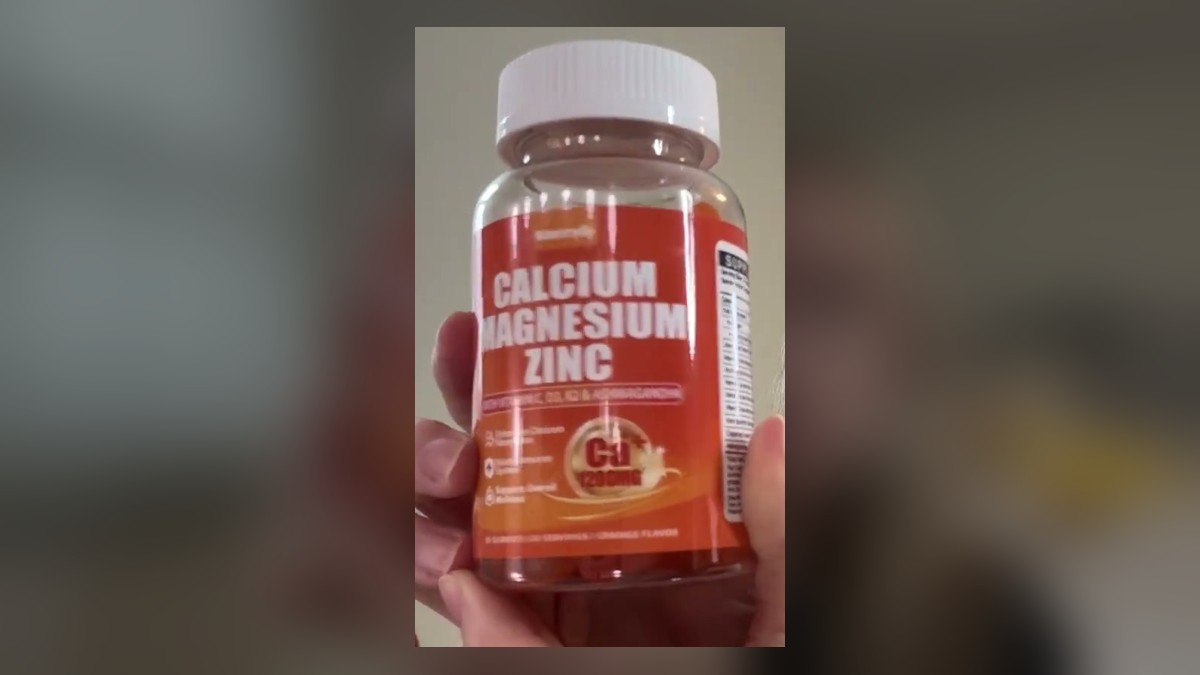 Orange bottle of Maennyliy Calcium Magnesium Zinc gummies with a white cap, held up with the 1200 mg calcium label facing forward