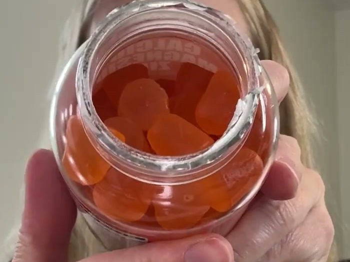 Looking down into an open bottle of Maennyliy calcium citrate gummies, filled with soft orange gummy squares