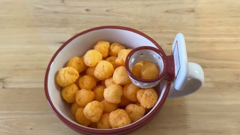 MAX'IS Creations Mug with a Hoop filled with cheese balls on a wooden table, with the mini basketball hoop and backboard on the rim above the handle