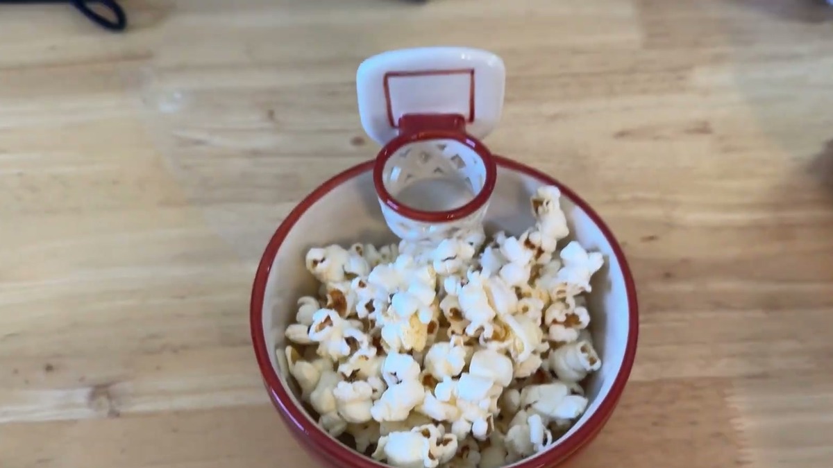 Top-down view of the MAX'IS Creations basketball mug used as a popcorn bowl, with the white backboard and hoop sticking up over the rim