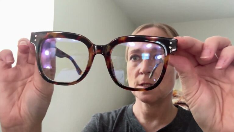miyya oversized blue light glasses held up straight on, showing the full chunky square tortoiseshell frame and the faint blue reflection on the clear lenses