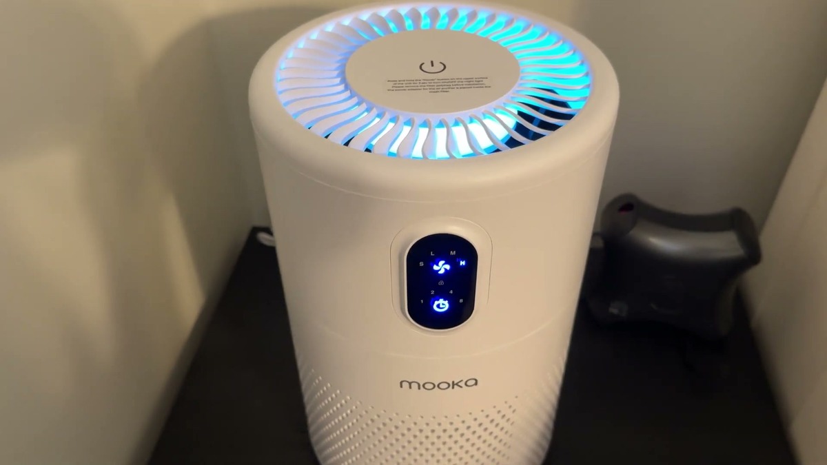 MOOKA air purifier running with its blue night light glowing through the top grille and the control panel lit up