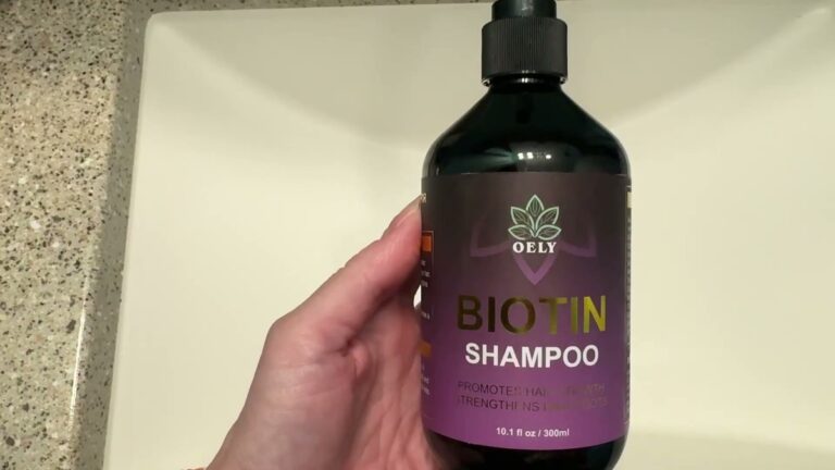 OELY Biotin Shampoo 10.1 ounce black pump bottle with a purple label held up in front of a bathroom sink