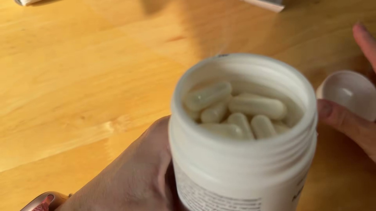 Open bottle of Olenphogy Magnesium-8 Pro filled to the top with white veggie capsules and no cotton filler