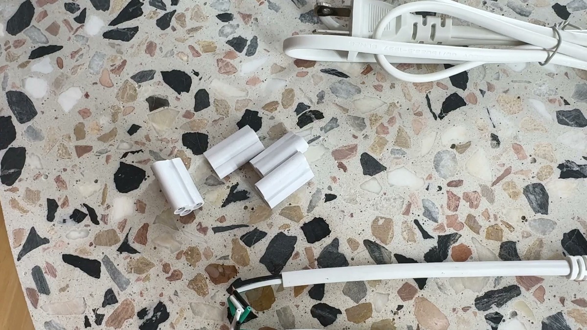 Pak LED shop light end-to-end link connectors, a link cable, and a plug-in power cord laid out on a terrazzo counter