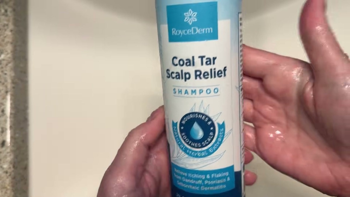 RoyceDerm coal tar shampoo bottle next to a hand covered in white lather at the sink