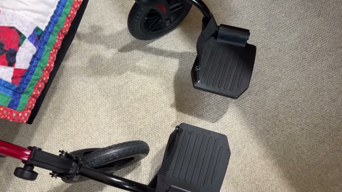 Flip-down footrests on the StrollAid rollator in transport chair mode, on carpet