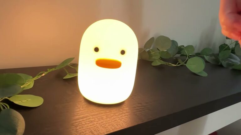 UNEEDE Benson duck silicone night light glowing a warm orange on a nightstand, a soft yellow duck-shaped lamp with a squeezable head
