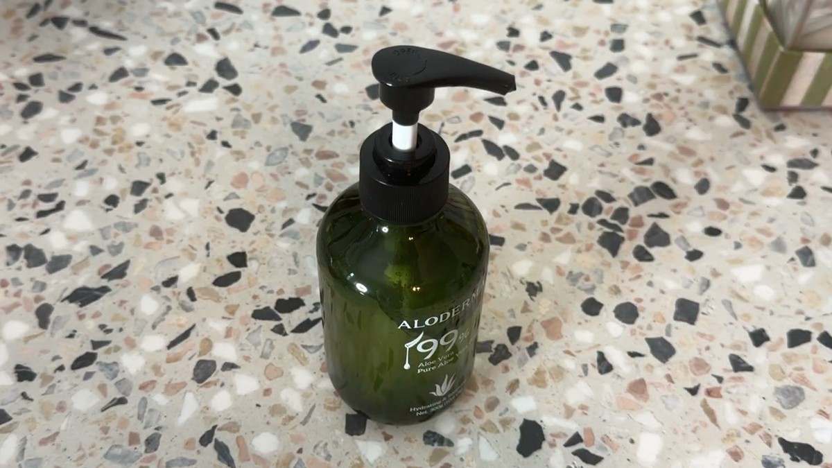 Green Aloderma 99% aloe vera gel pump bottle standing on a speckled terrazzo counter