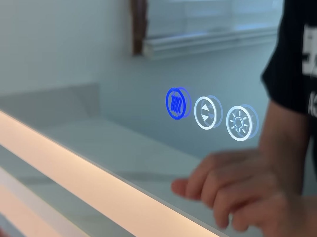 Close-up of the Amorho mirror's three touch buttons on the glass, with the anti-fog button glowing blue next to the dimmer and light buttons.