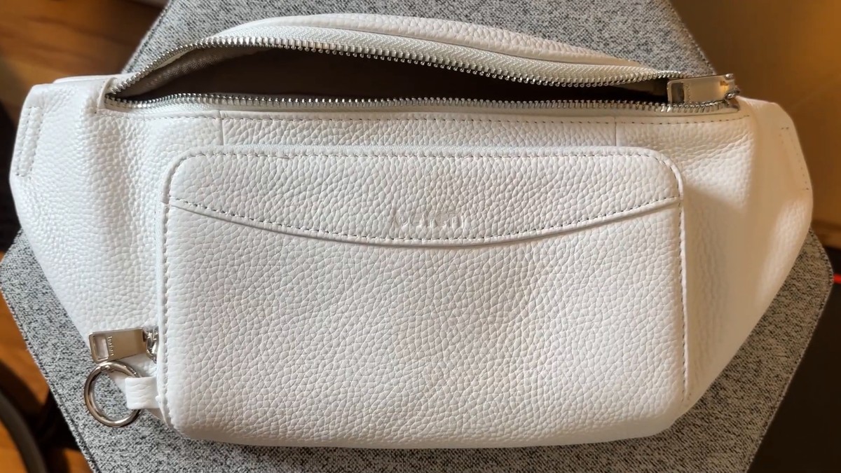 White pebbled leather befen fanny pack with a zippered front pocket, silver zipper and a silver ring clip on the side.