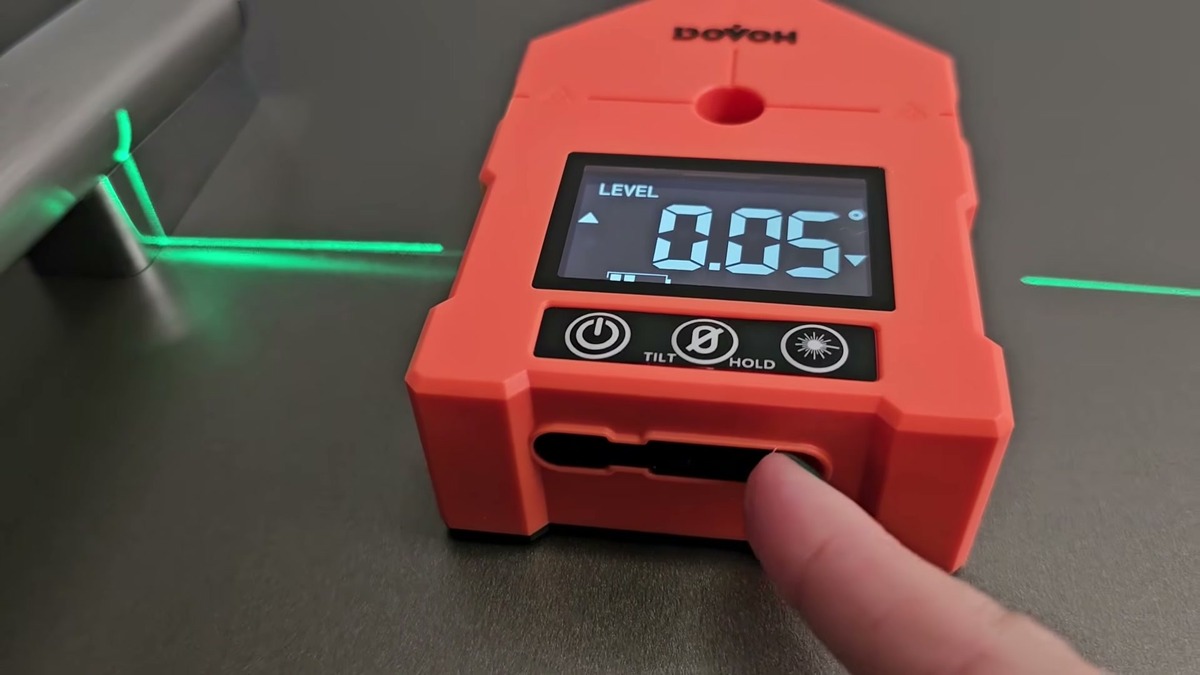 Orange DOVOH WG-3L digital angle finder with its screen reading 0.05 degrees and green laser lines shooting out both sides