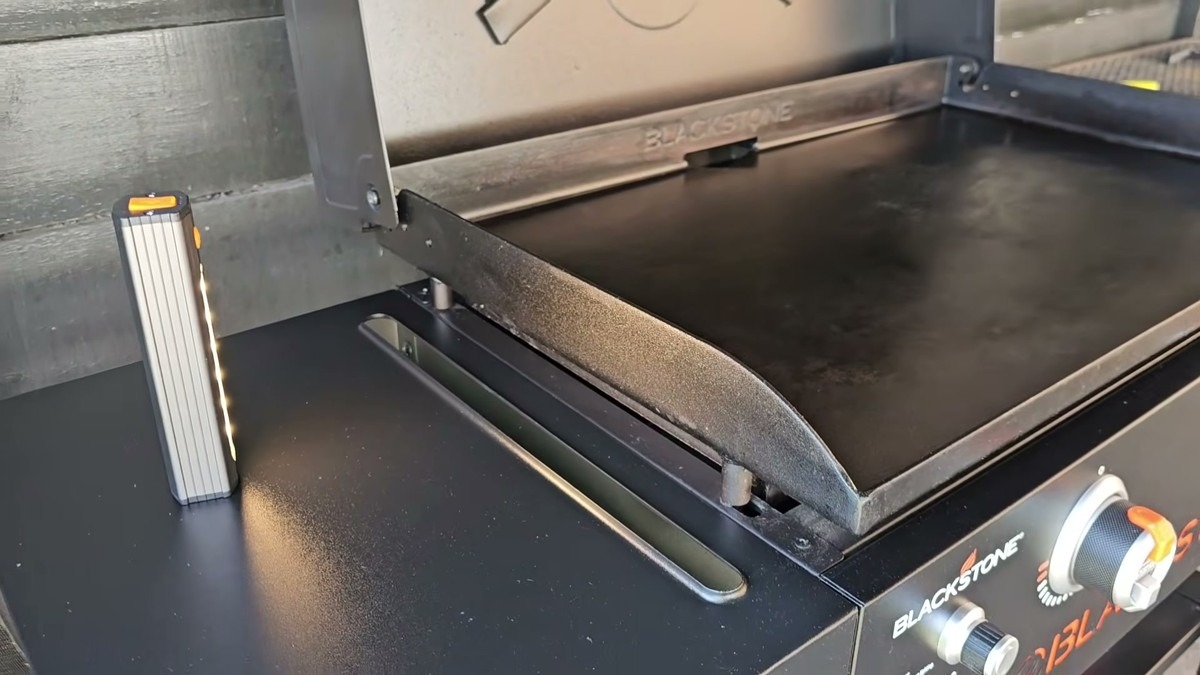 Grill light detached from its handle mount and standing on its magnetic base on the Blackstone side shelf next to the open griddle