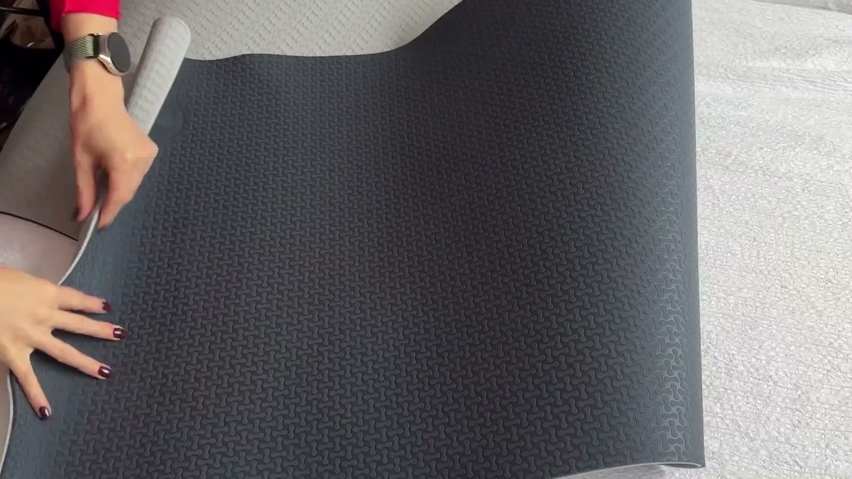 IUGA yoga mat half unrolled, showing the dark gray textured side next to the light gray side