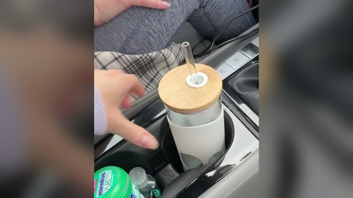 Bonesy glass tumbler with its bamboo lid and glass straw sitting in a car's center console cup holder
