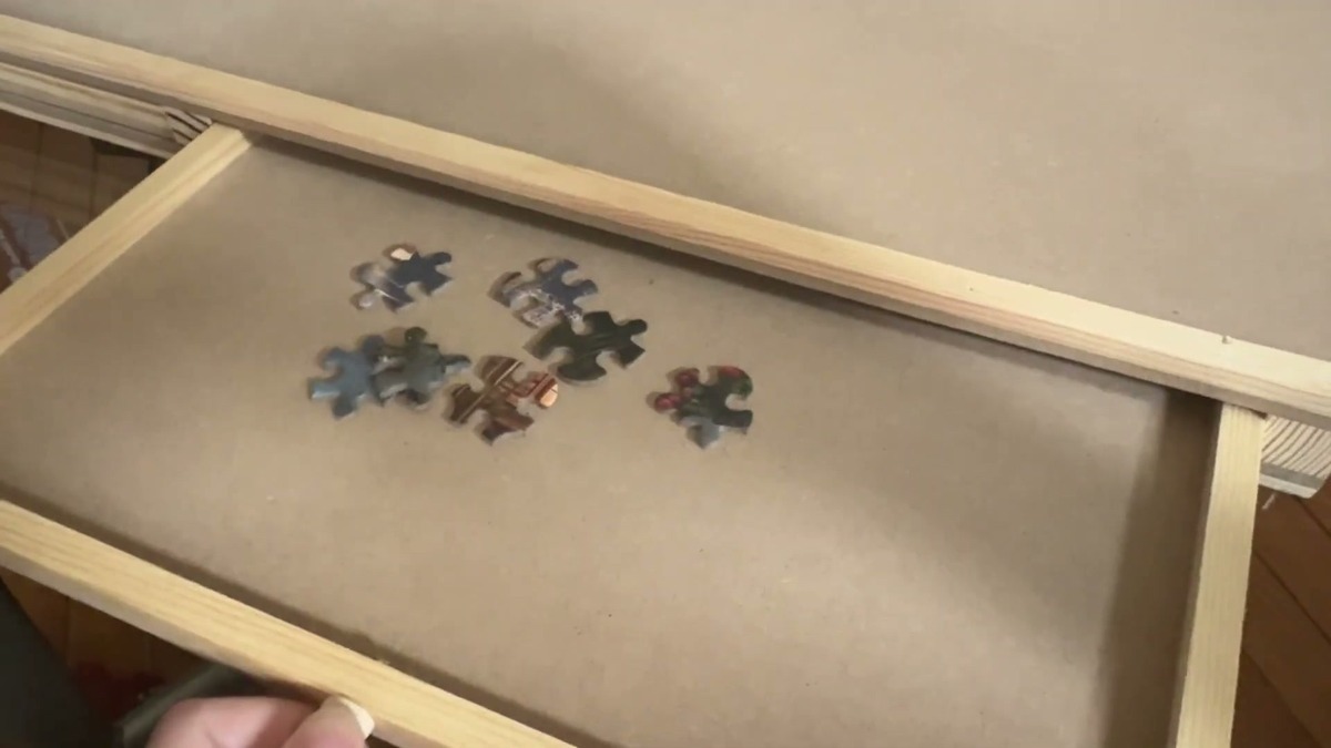 One of the PlayVibe puzzle board's wooden drawers pulled open with a few puzzle pieces inside