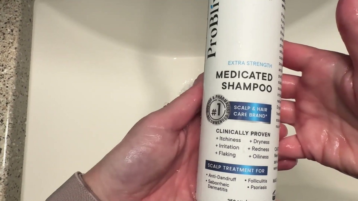 White ProBliva Extra Strength Medicated Shampoo bottle held over a bathroom sink with the front label facing up