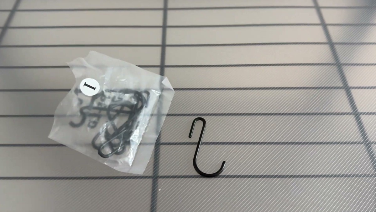 Black S-shaped hook and a bag of extra hooks resting on a SONGMICS wire shelf liner