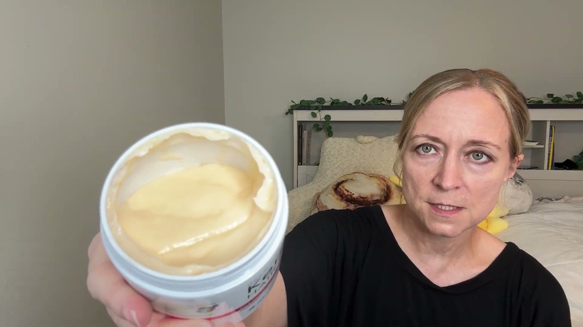 Open jar of SUNATORIA keratin hair mask held toward the camera showing the pale yellow cream inside