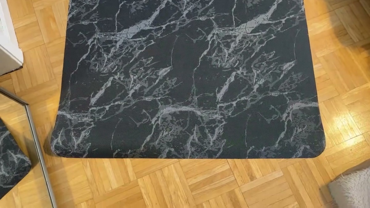 Vaukki 36 x 48 inch chair mat with a black and white marble pattern lying flat on a light hardwood floor