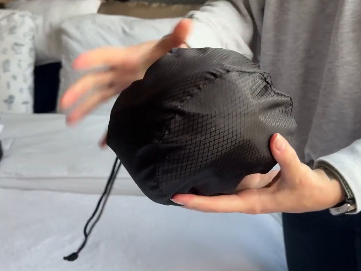 WEERSHUN travel pillow squeezed into its black drawstring storage pouch, held in two hands